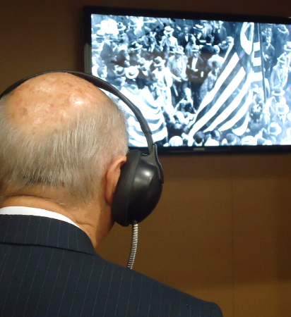 Foto de homem com fone em frente a uma tela de TV